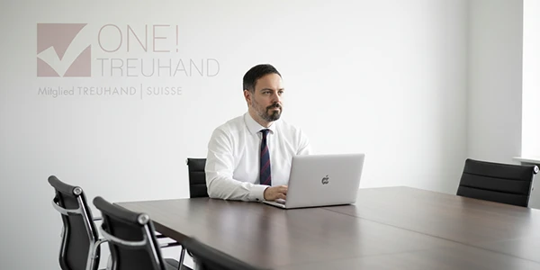 Ein Berater arbeitet konzentriert an einem Laptop in einem modernen Konferenzraum, ideal für Treuhand-Dienstleistungen.