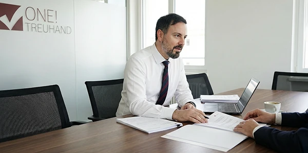 Ein Steuerberater bespricht Verträge und unterstreicht präzise Treuhand-Dienstleistungen in einer professionellen Umgebung.